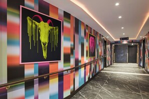Un pasillo con paredes de rayas de colores, piso de mármol y un letrero que indica un gimnasio.