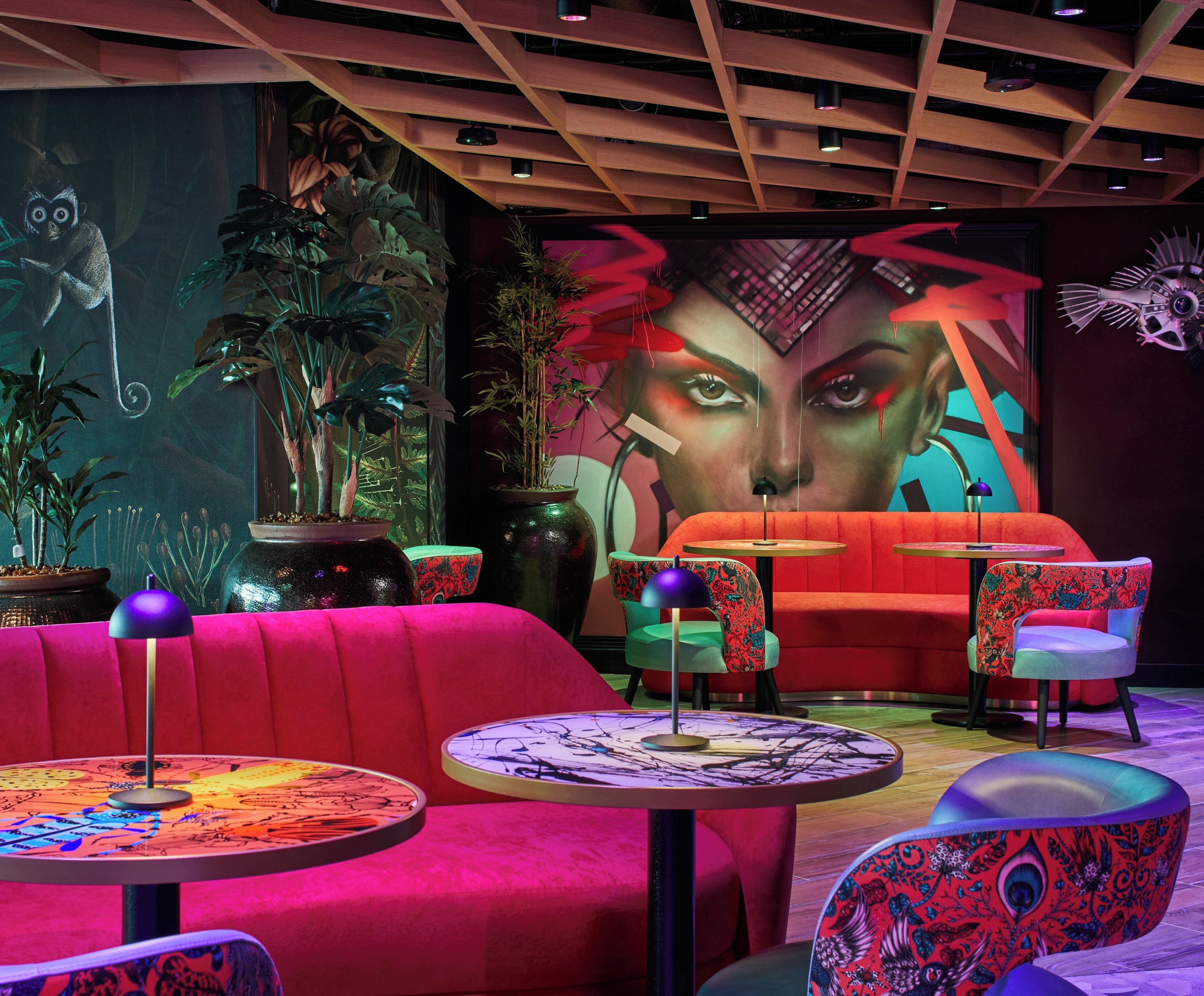 A modern lounge area with vibrant seating, a large mural, and ambient lighting.