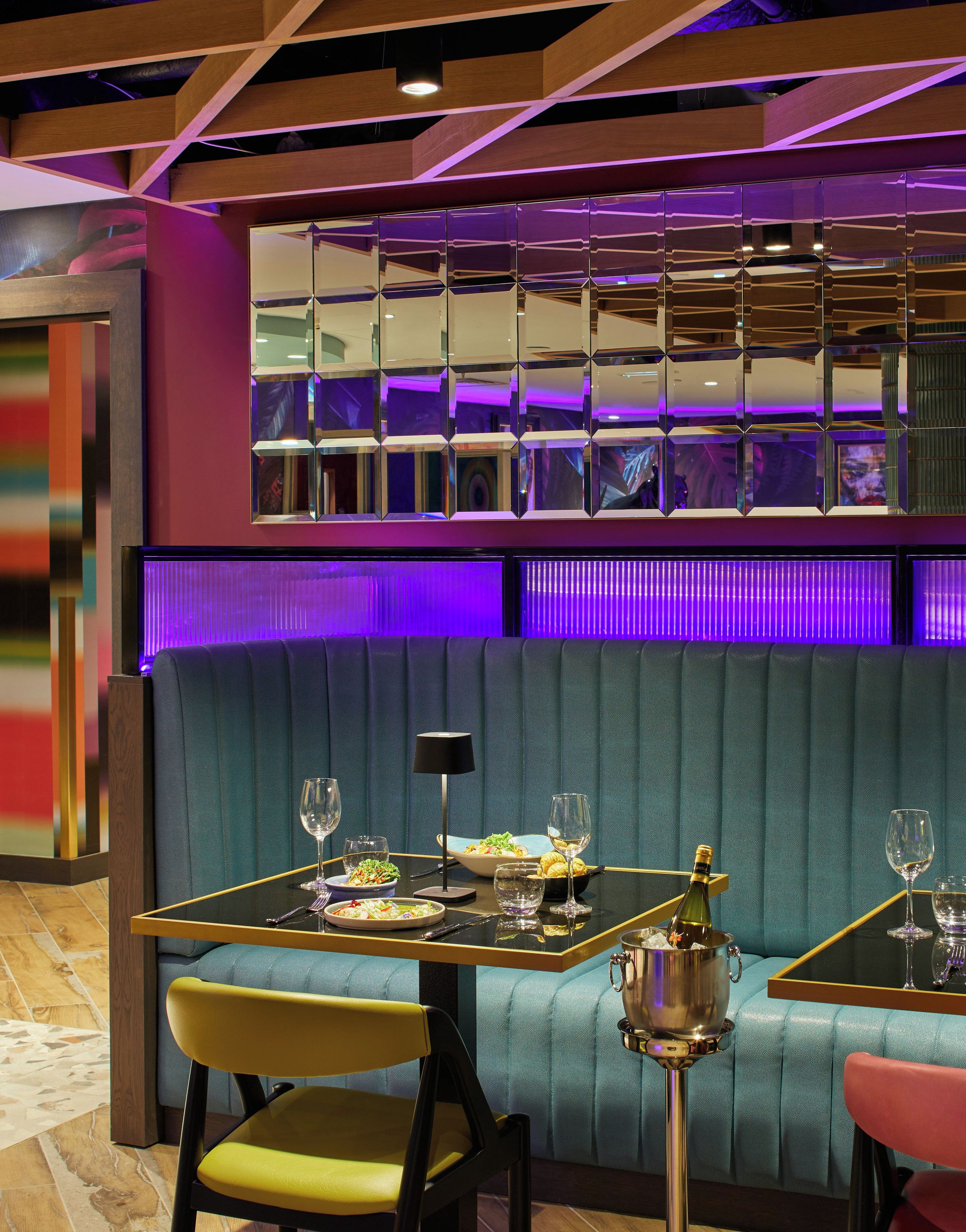 Interior de restaurant amb zona de seients en cabines, una taula preparada amb plats, vasos i una ampolla de xampany.