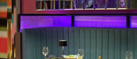 A restaurant interior with a booth seating area, a table set with plates, glasses, and a bottle of champagne.