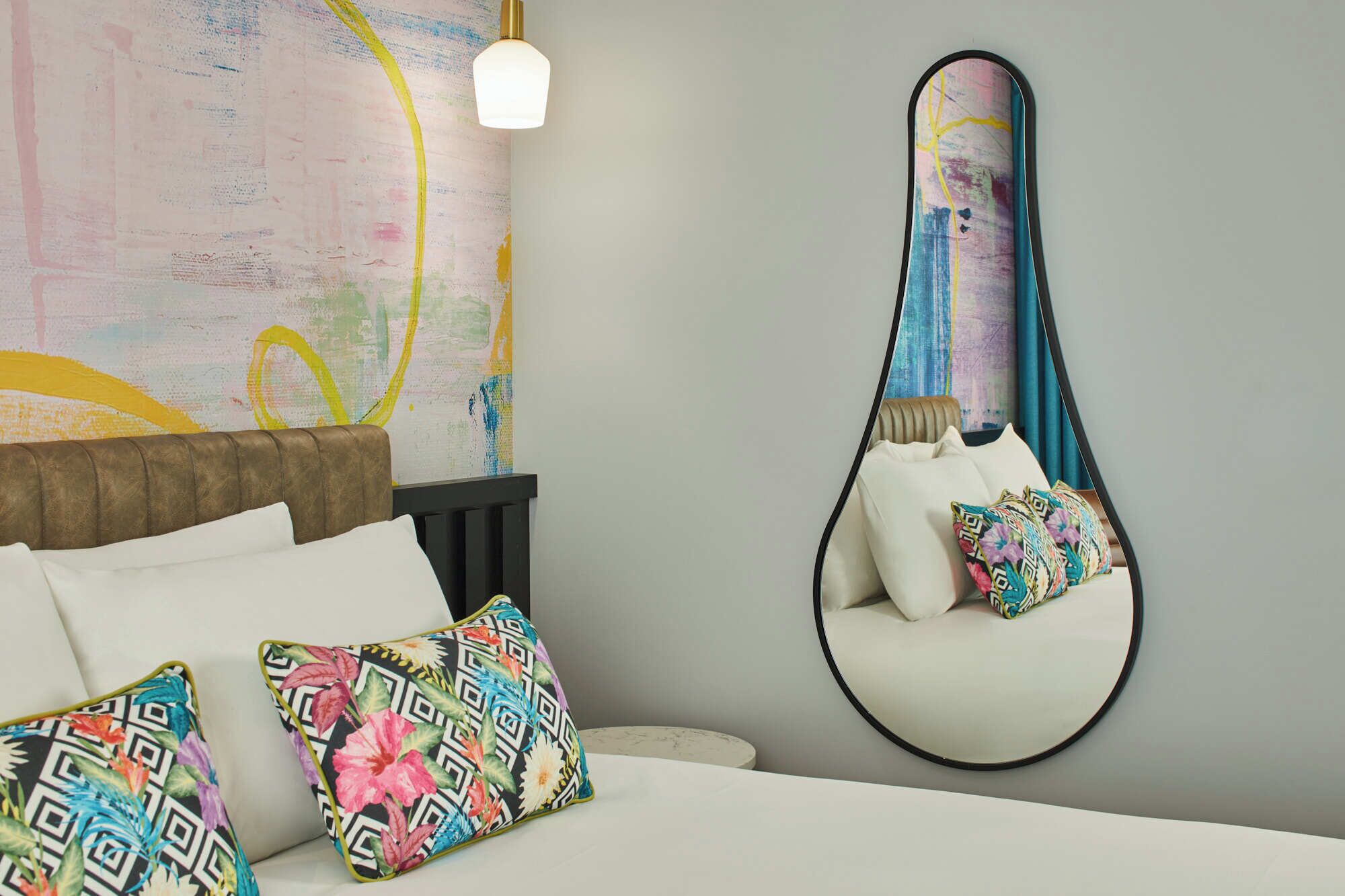 Een slaapkamer met een bed, kussens, een hangstoel, een wanddecoratie en een lamp.