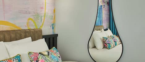 A bedroom with a bed, pillows, a hanging chair, a wall art, and a light fixture.