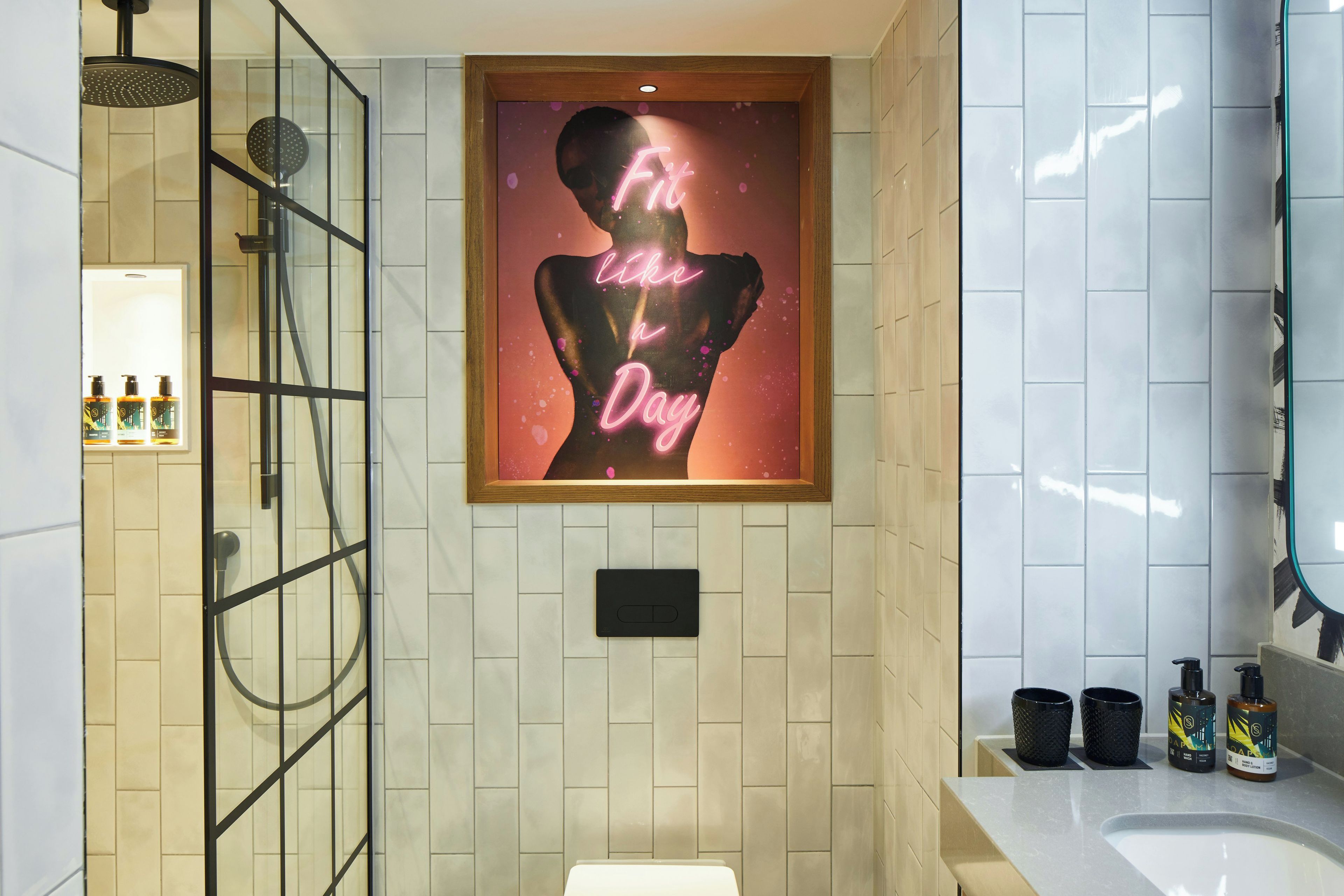 A bathroom with a shower, a sink, and a framed artwork on the wall.