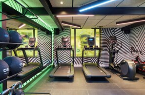 Une salle de sport équipée de tapis de course, d’un vélo d’appartement et de matériel de musculation.