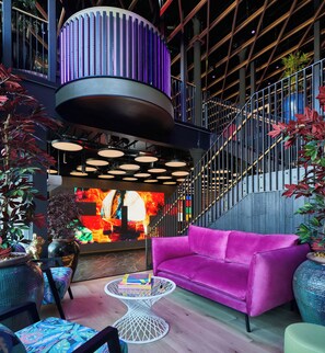 Un intérieur moderne avec un canapé violet, une table ronde et un escalier.