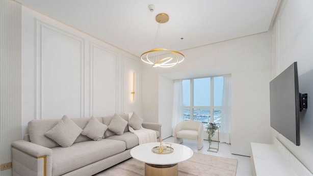 Una sala de estar moderna con un sofá color beige, una mesa de centro redonda y un televisor grande.