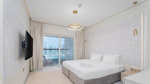 Habitación de hotel moderna con una cama grande, un televisor de pantalla plana, un balcón con vista a la ciudad y una decoración minimalista.