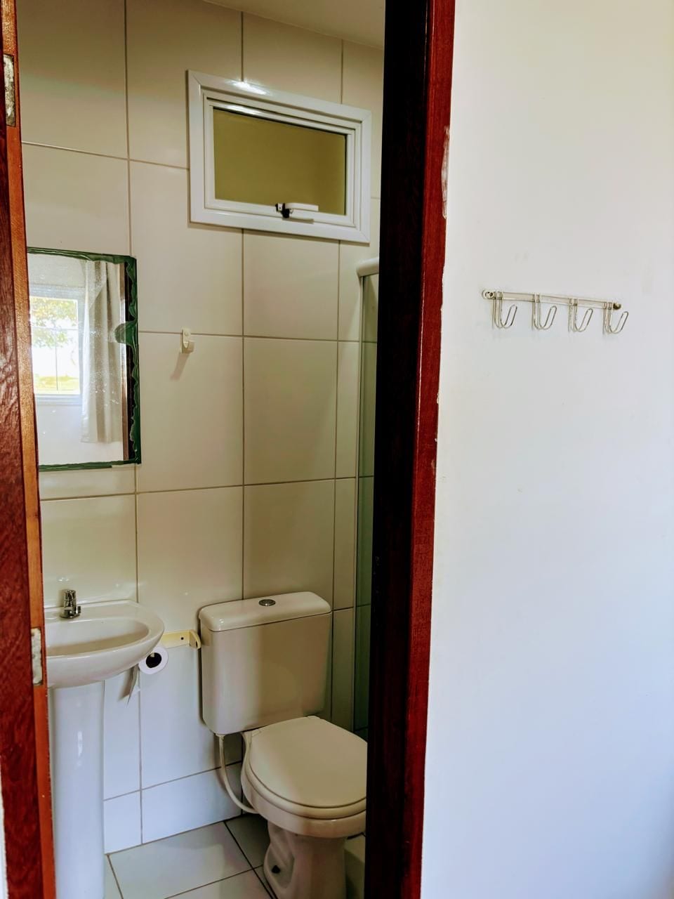 A bathroom with a toilet, sink, and mirror.