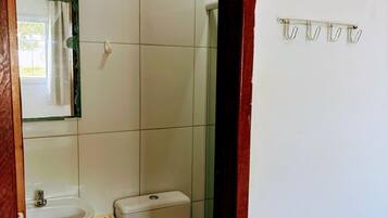 A bathroom with a toilet, sink, and mirror.