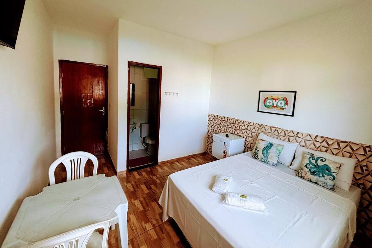 A hotel room with a bed, a desk, a chair, and a bathroom visible through an open door.