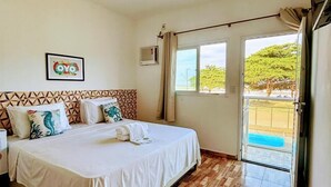 A hotel room with a bed, a picture of an owl, a window, and a door leading outside. - POUSADA SOL & MAR (Serra)