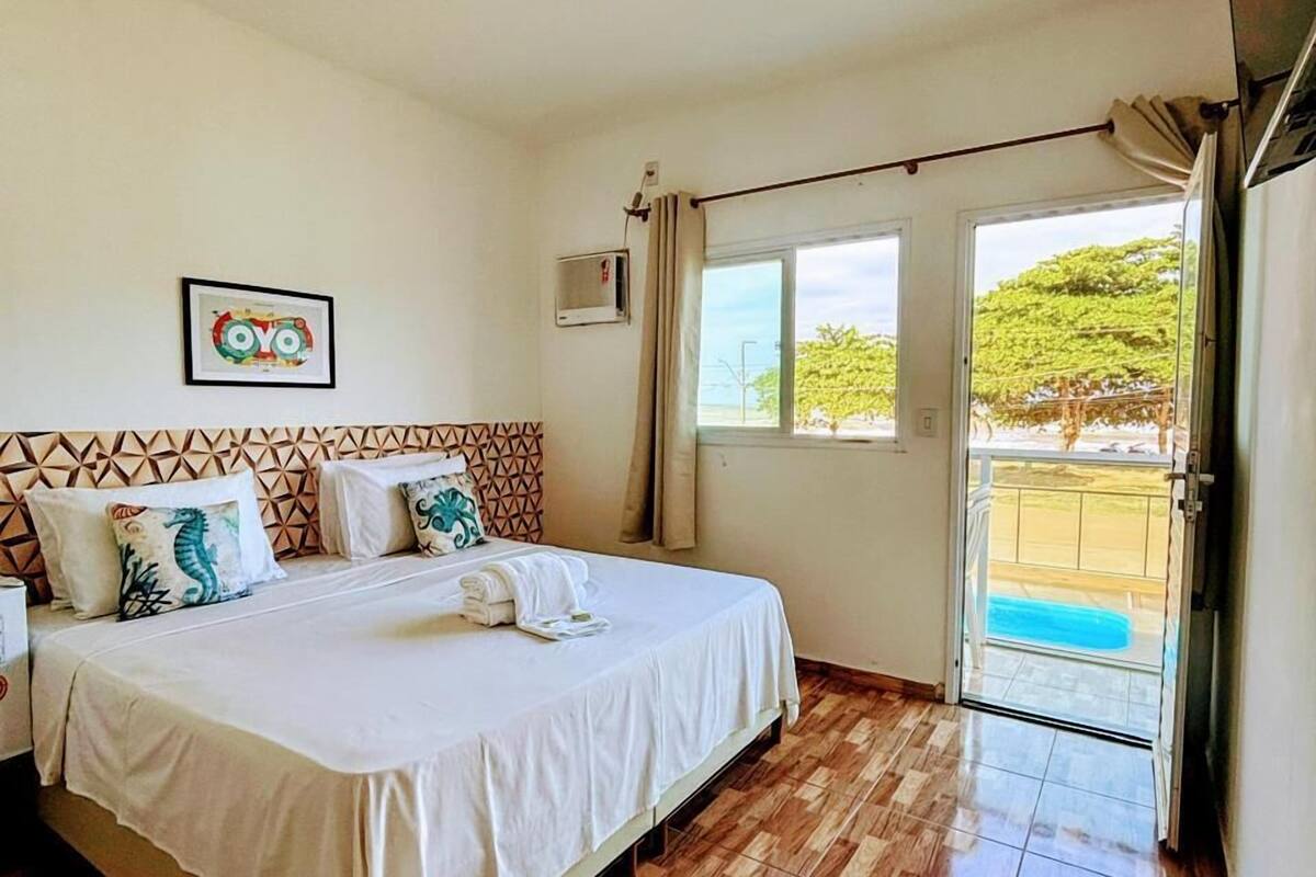 A hotel room with a bed, a picture of an owl, a window, and a door leading outside.