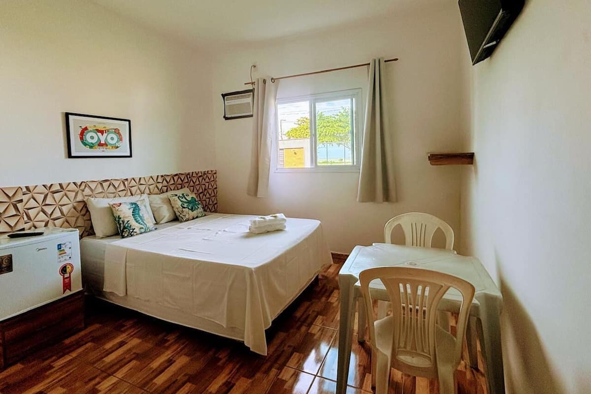A room with a bed, a desk, a chair, a TV, and a window with curtains.