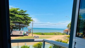 A balcony with a view of the beach, a truck, and a building in the background. - POUSADA SOL & MAR (Serra)