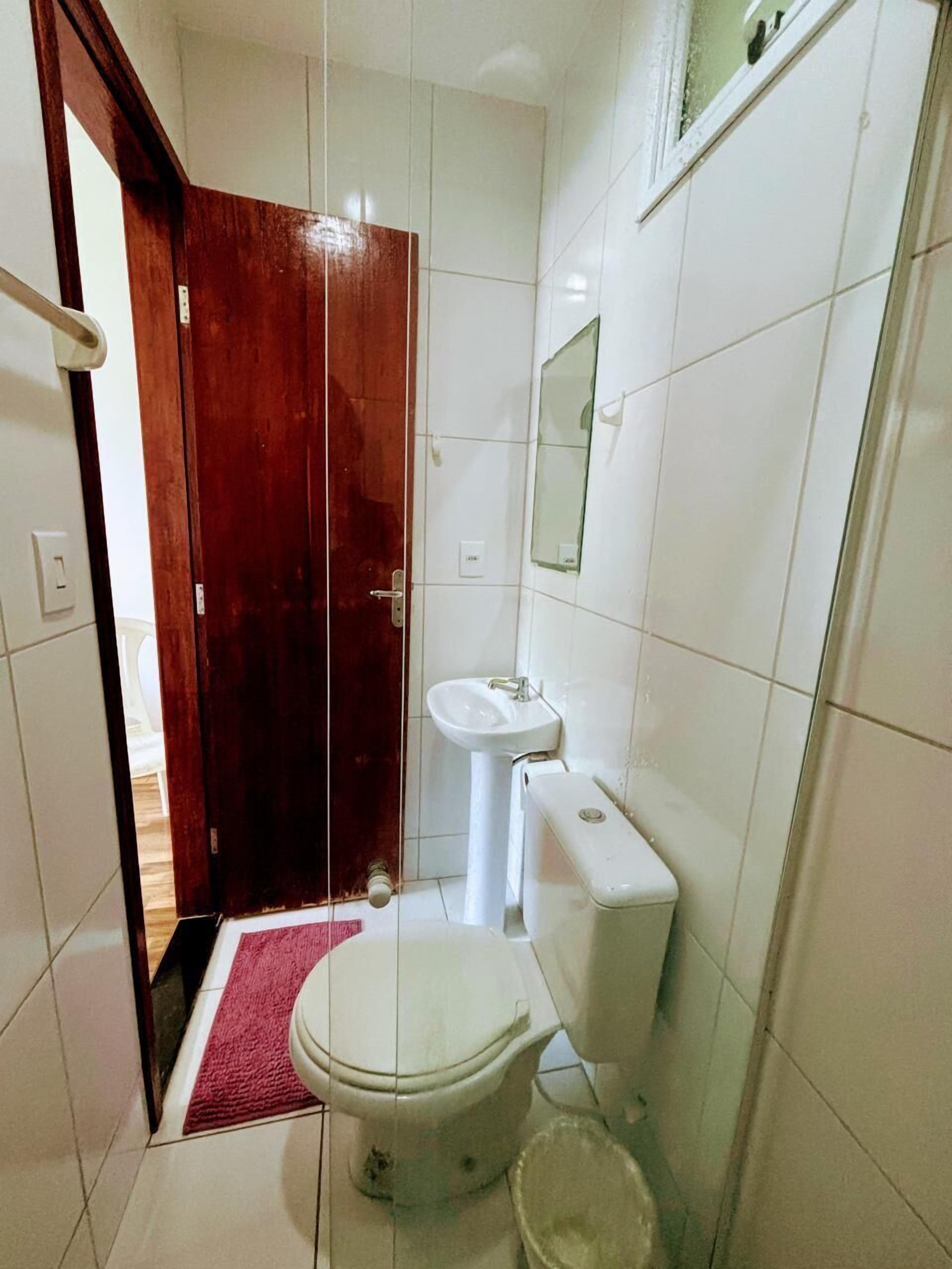 Un baño pequeño con inodoro, lavamanos y puerta de madera.