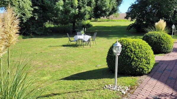 A well-maintained garden with a table and chairs, neatly trimmed hedges, and a pathway. - Apartment im Maritimen Flair Inmitten Ländlicher Idylle! (Katzow)