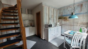 A compact kitchen with white cabinets, a microwave, and a small dining area with a table and chairs.