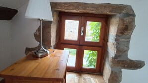 Une pièce rustique avec une table en bois, une lampe et un mur en pierre.