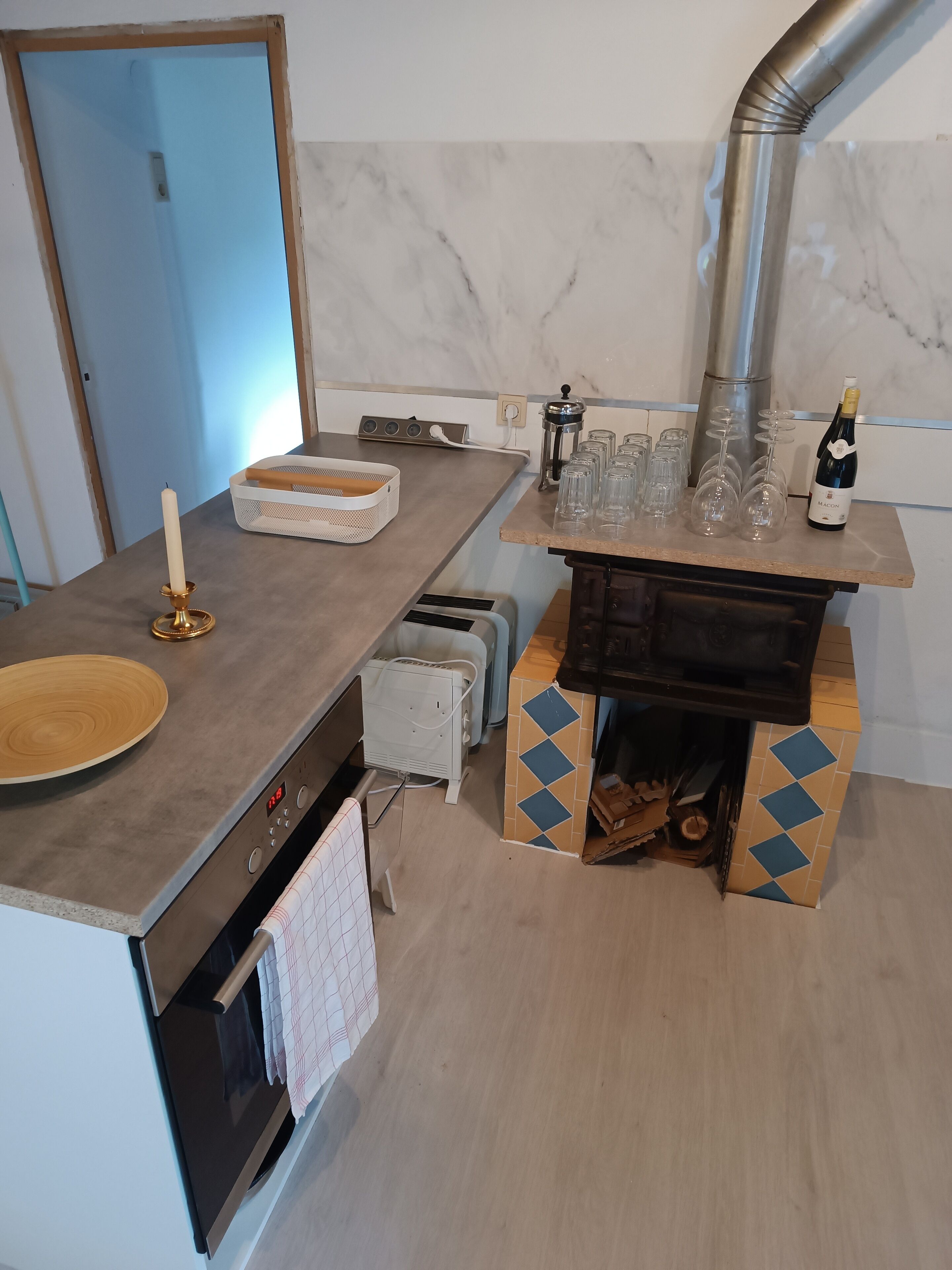 A modern kitchen with a marble backsplash, a built-in oven, and a coffee machine.