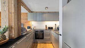 A modern kitchen with wooden accents, stainless steel appliances, and a wooden floor. - Cabane de la Delege -crans Montana- Amazing Views (Lens)