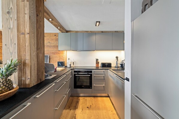 A modern kitchen with wooden accents, stainless steel appliances, and a wooden floor.
