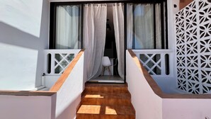 A wooden staircase leading to a balcony with white railings and a patterned wall. - Apartamento Julia (Costa Adeje)