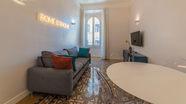 Un salon moderne avec un canapé, une table à manger, un téléviseur et un sol à motifs.