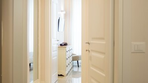 Un couloir avec une porte blanche, un miroir et une petite table sur laquelle se trouve une lampe.
