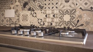 Une cuisine équipée d’une cuisinière à gaz et dont le mur est décoré de carreaux à motifs.