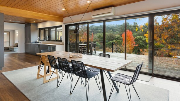 A modern kitchen with a large island, wooden ceiling, and large windows offering a view of autumn foliage. - Delatite Valley: 4  BR, 3.5  BA House in Merrijig, Sleeps 12 (Merrijig)