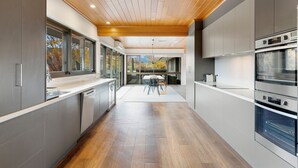 A modern kitchen with wooden flooring, built-in appliances, and large windows. - Delatite Valley: 4  BR, 3.5  BA House in Merrijig, Sleeps 12 (Merrijig)