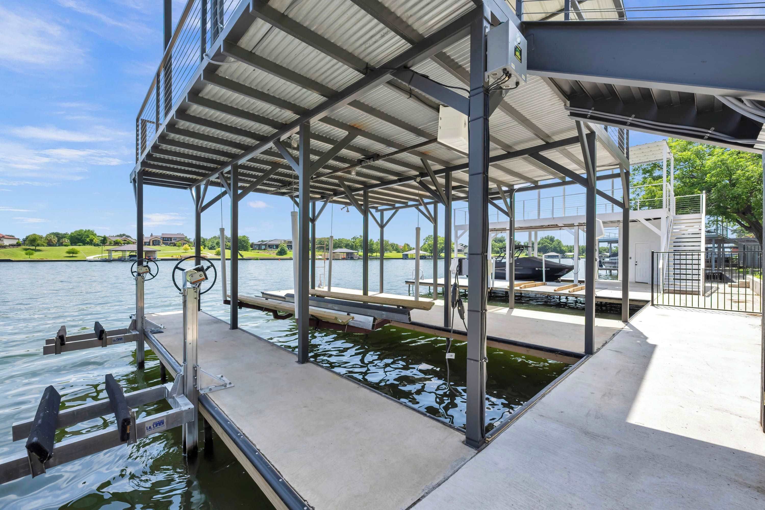 A covered dock with a metal railing, a concrete platform, and a water body.