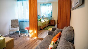 Une pièce comprenant un canapé, un fauteuil, un lit et un miroir.