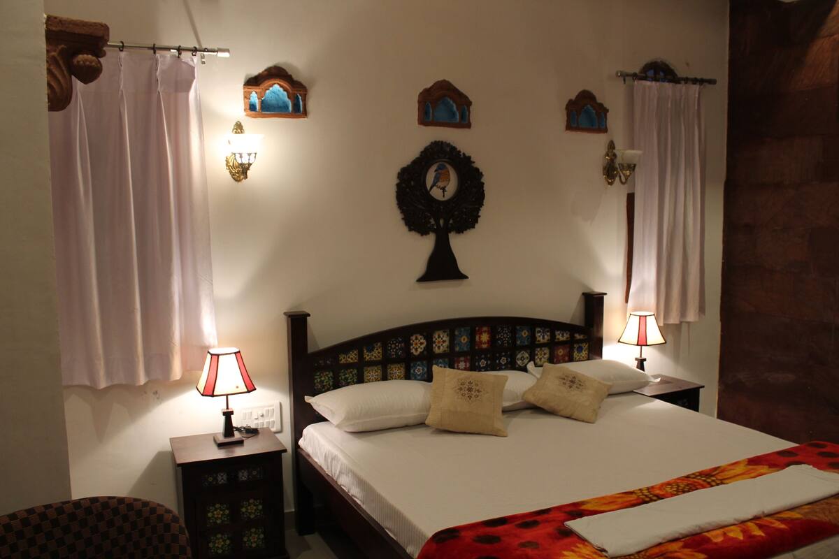 A bedroom with a bed, two nightstands, a wall-mounted lamp, and a decorative wreath.