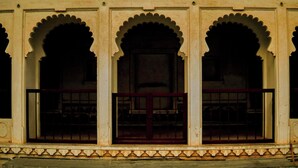 A building facade with three arched windows and a central door, framed by ornate stonework. - Kesar Heritage Guest House  (Jodhpur)