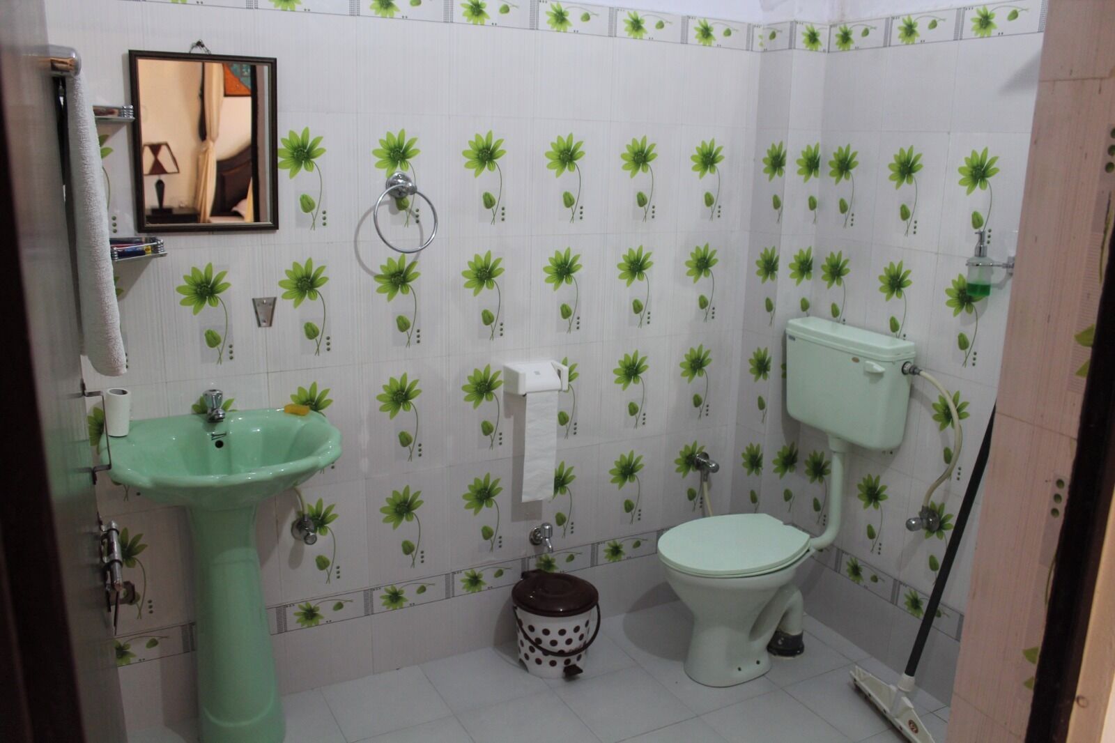 A bathroom with a green sink, toilet, and a mirror.