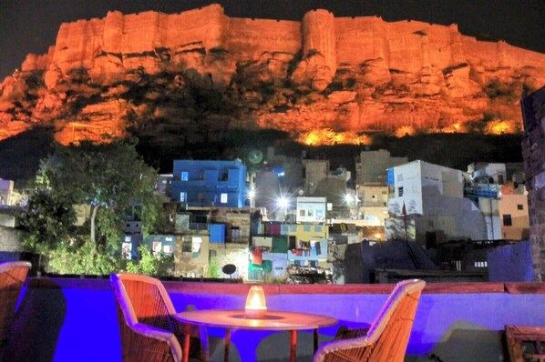 Une terrasse avec une table et des chaises, donnant sur une colline densément bâtie.