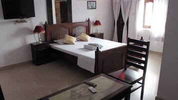 A bedroom with a bed, bedside tables, a TV, a chair, and a table with a remote control.