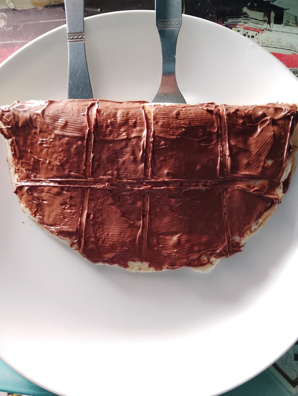 Une assiette blanche sur laquelle se trouve un dessert enrobé de chocolat.