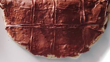 Une assiette blanche sur laquelle se trouve un dessert enrobé de chocolat.