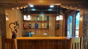 Una zona de bar con paneles de madera, luces colgantes y una barra.