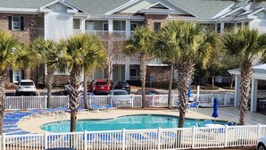 A pool area with lounge chairs and a swimming pool, surrounded by a white fence. - The retreat at Magnolia (Myrtle Beach)