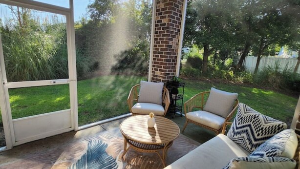 A sunroom with a large glass door, a ceiling fan, wicker furniture, and a decorative rug. - The retreat at Magnolia (Myrtle Beach)