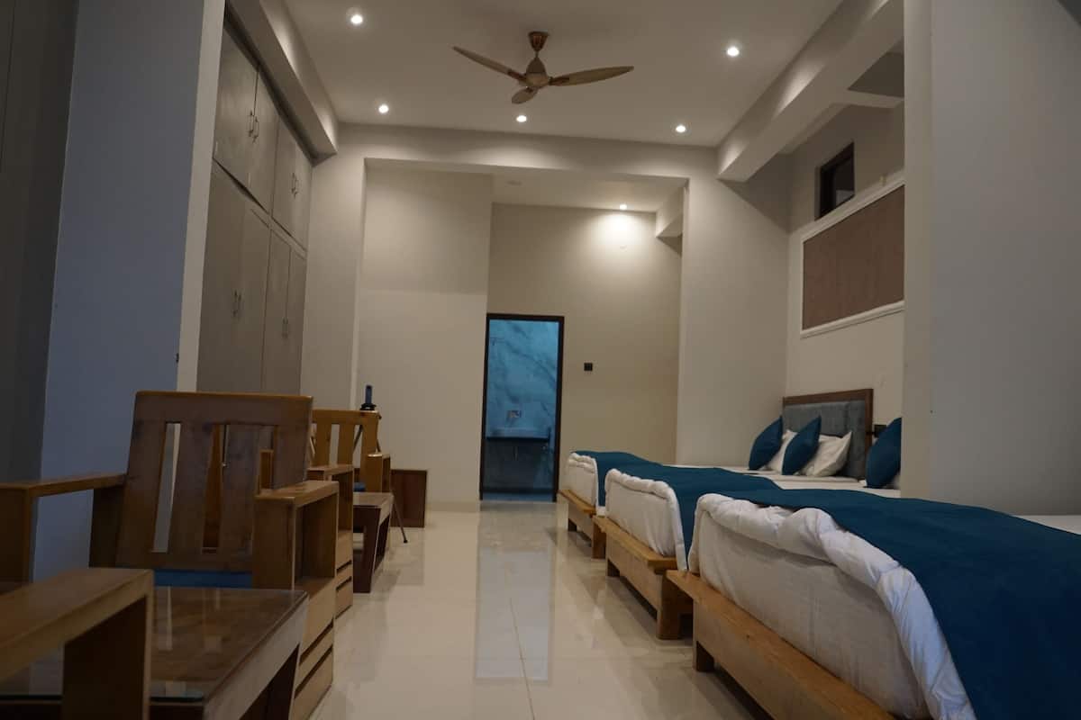 A modern hotel room with a large bed, a smaller bed, a desk, and a chair.