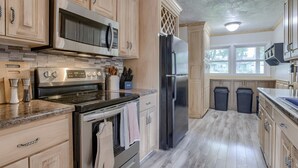 A kitchen with wooden cabinets, stainless steel appliances, and a tiled backsplash. - 5BD Charming Home - Pool Table & Backyard (Omaha)