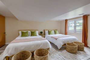 Een hotelkamer met twee bedden, een groot raam met gordijnen en rieten manden op de vloer.
