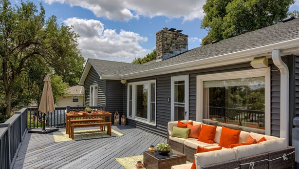 A covered deck with outdoor furniture, a dining table, and a stone fireplace. - 5BD Charming Home - Pool Table & Backyard (Omaha)