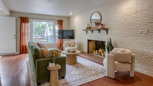 A living room with a fireplace, a television, and a sofa. - 5BD Charming Home - Pool Table & Backyard (Omaha)
