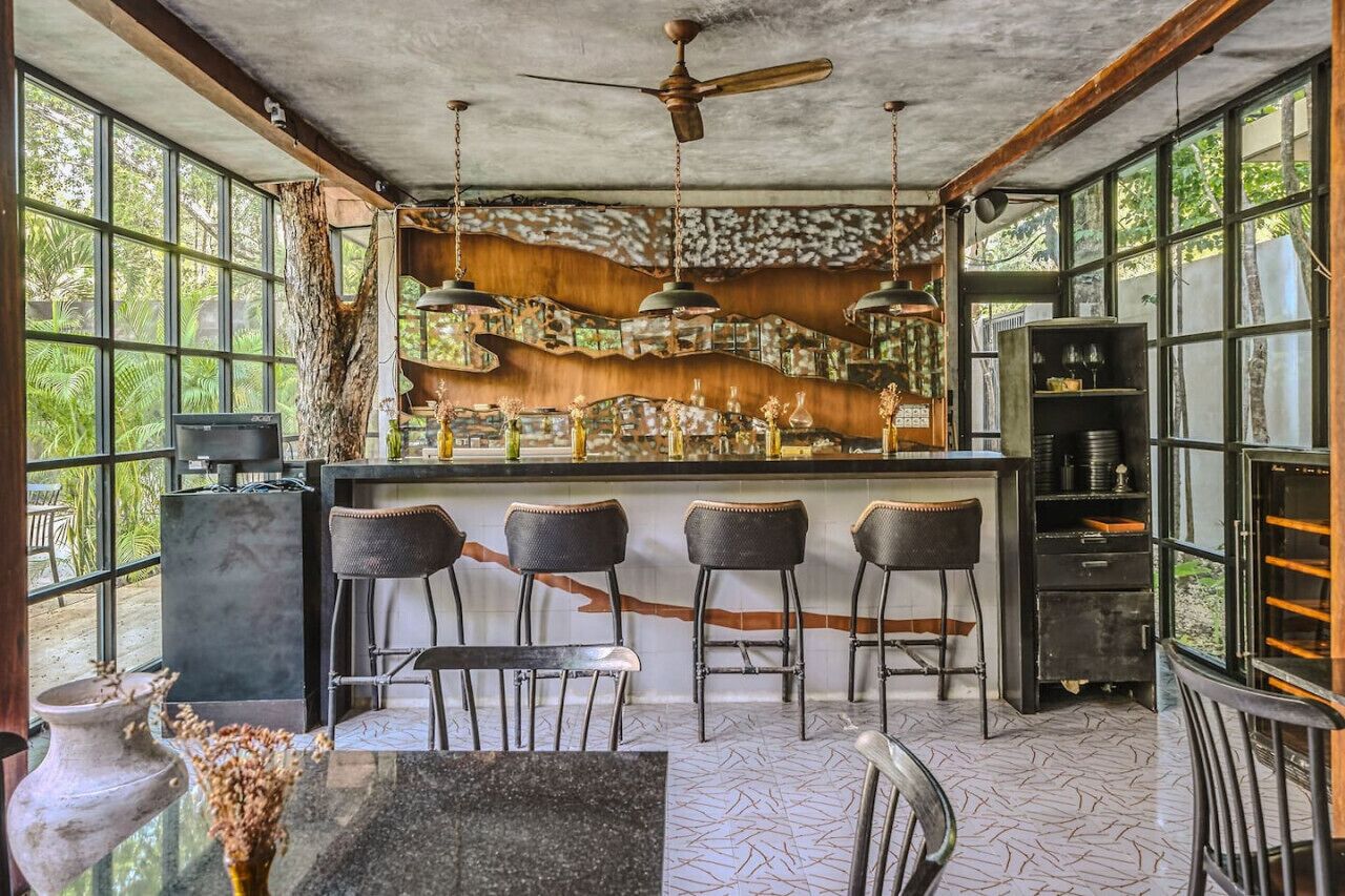Un'area bar dall'arredamento rustico, con un bancone in legno e sgabelli in metallo.