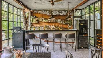 Un'area bar dall'arredamento rustico, con un bancone in legno e sgabelli in metallo.